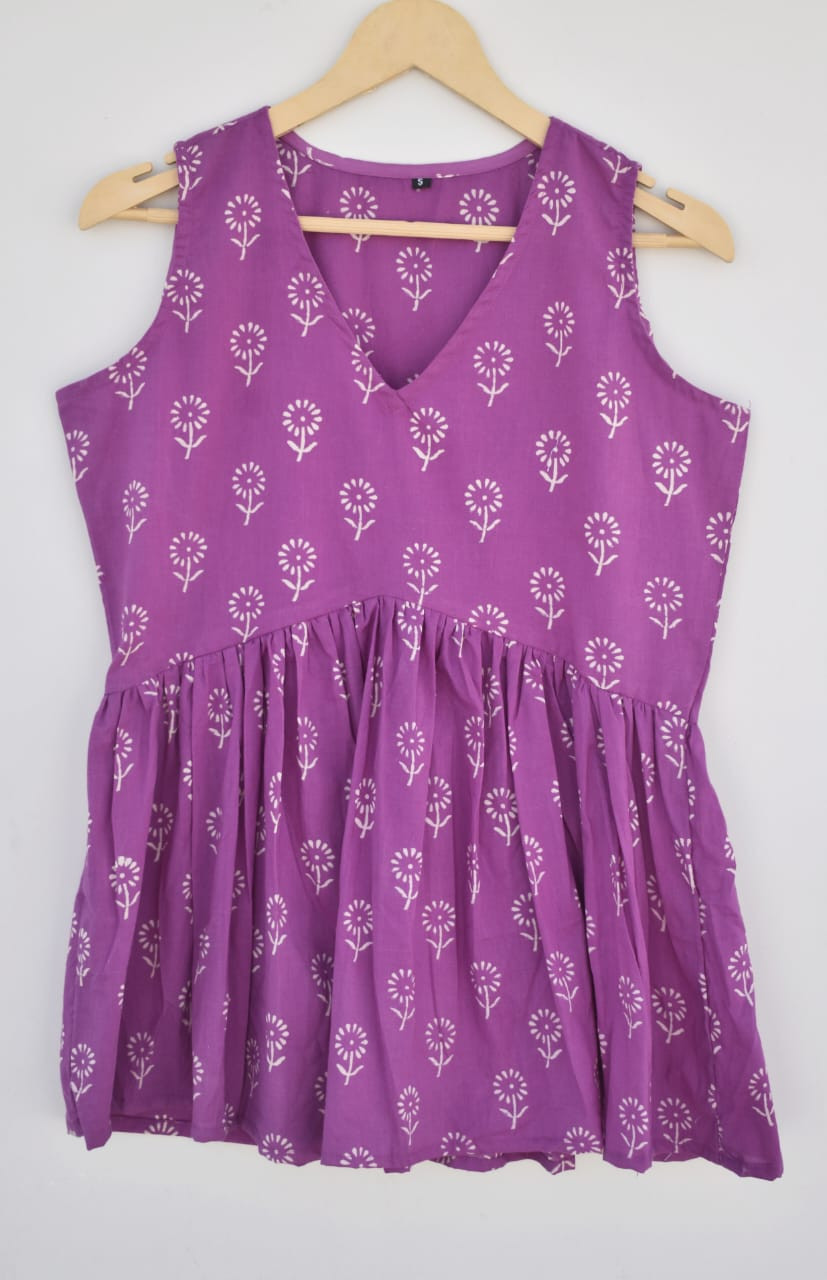 a purple, hand-block printed, cotton, sleeveless peplum top with a white floral or vine pattern.