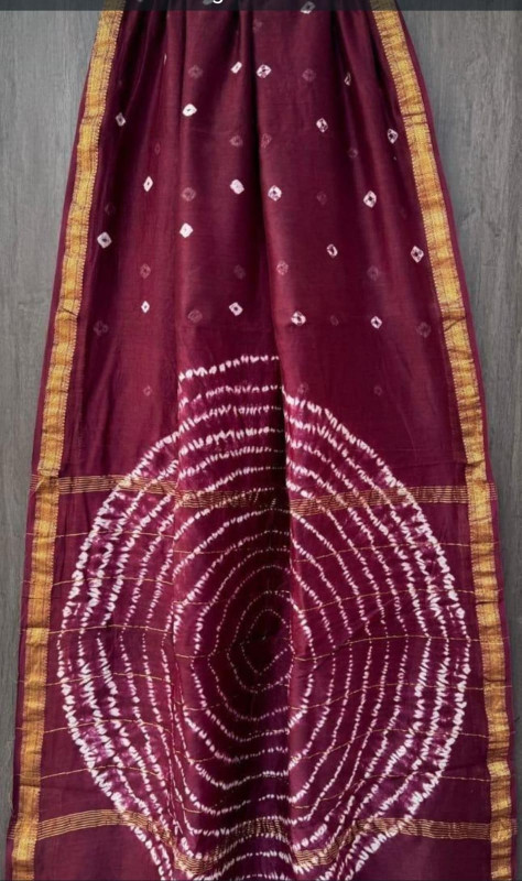 maroon tie-dye (Bandhani or Shibori) Maheshwari silk/cotton blend saree with traditional motifs and a golden zari border.